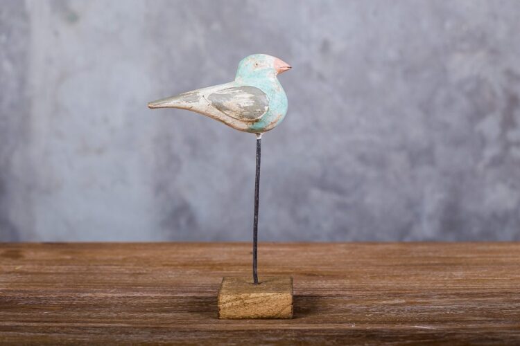 Pájaro de madera celeste sobre pedestal