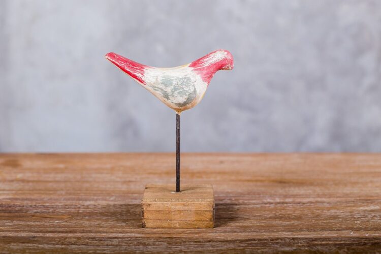 Pájaro de madera sobre pedestal